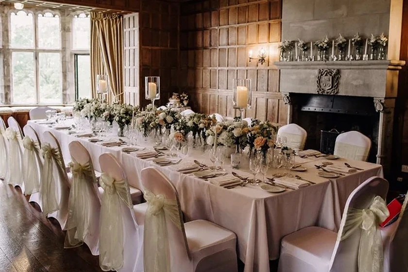 Dining set-up with red banqueting chairs, white covers and gold bows in the west wing ceremony room